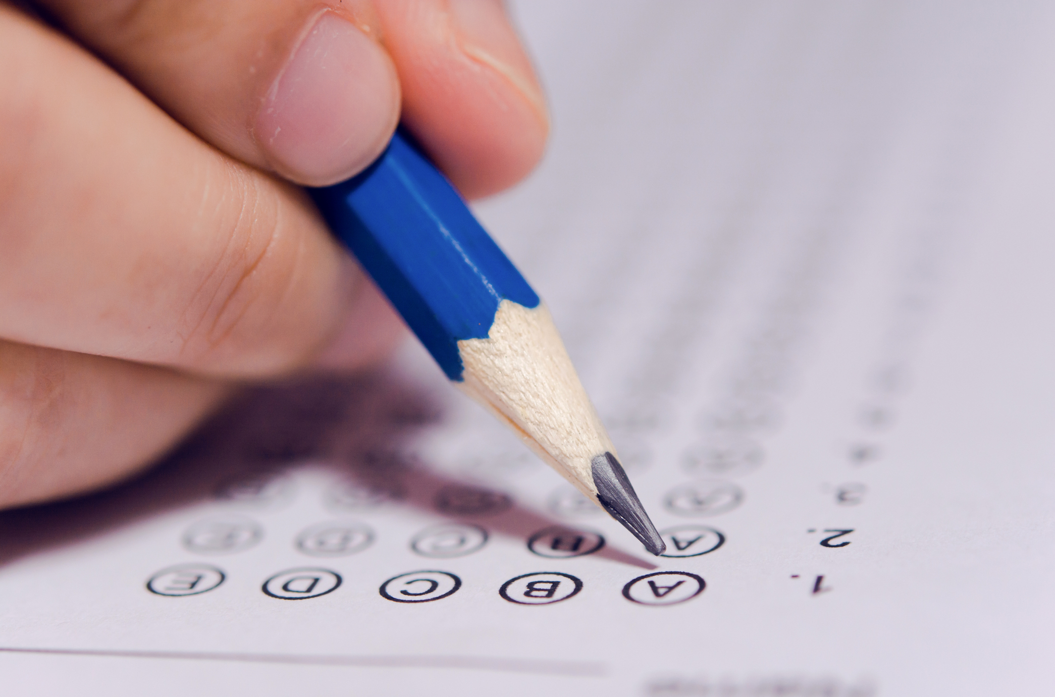 Students hand holding pencil writing selected choice on answer sheets and Mathematics question sheets. students testing doing examination. school exam